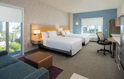 a hotel room with two beds and a couch at Home2 Suites By Hilton Ft. Lauderdale Downtown, Fl in Fort Lauderdale