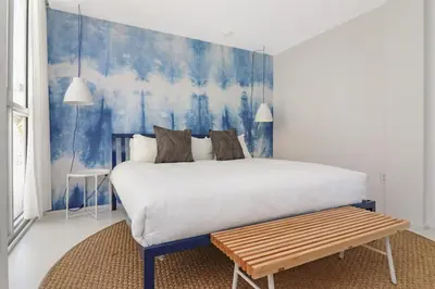 a bedroom with a large bed and a bench at Roami at 250 Collins in Miami Beach