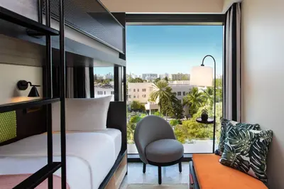 a bedroom with a bed and a chair and a window at Moxy Miami South Beach in Miami Beach