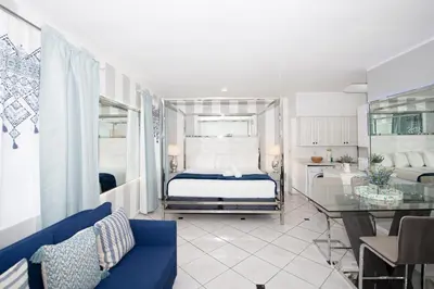 a bedroom with a king sized bed and a kitchen at Apartments on Collins in Miami Beach