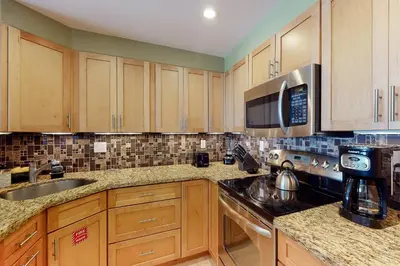 a kitchen with wooden cabinets and a sink and a microwave at Paradise Perch in Fort Lauderdale