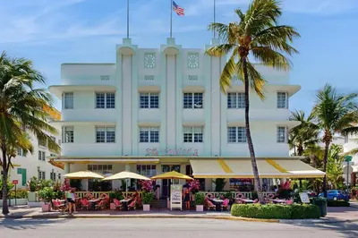 a large white building with palm trees in front of it at The Carlyle 3G in Miami Beach