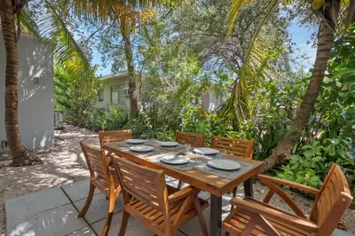a wooden table and chairs on a patio with trees at Casa Nikoleta Gated 3Bd 2Bth 10 Min to Beach in Miami