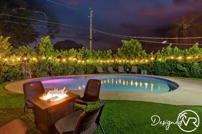 a backyard with a pool with chairs and a fire pit at 4BR retreat w heated pool backyard BBQ grill in Dania Beach