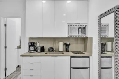a kitchen with white cabinets and a sink at Cozy studio wbeach boardwalk steps kitchen in Hollywood