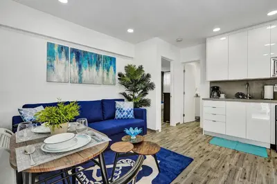 a living room with a blue couch and a kitchen at Cozy studio wbeach boardwalk steps kitchen in Hollywood
