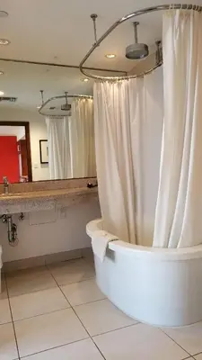 a bathroom with a bath tub and a mirror at VERSACE MANSION VIEW SUITE at THE STRAND in Miami Beach