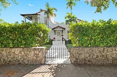 a white house with a gate and trees at Casa Coral in Miami