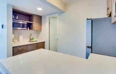 a kitchen with a white counter and a refrigerator at Castle 835 Oceanview studio on beach with pool, gym, bars, and FREE Parking in Miami Beach