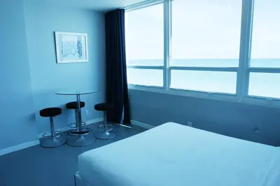 a bedroom with a bed and two stools in front of a window at Castle 835 Oceanview studio on beach with pool, gym, bars, and FREE Parking in Miami Beach