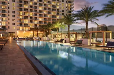 a swimming pool with chairs and a large building at Luxury Condo with Jacuzzi and Amenities in Hollywood