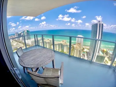 a balcony with a table and chairs and the ocean at Luxury Condo with Jacuzzi and Amenities in Hollywood