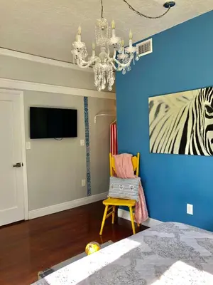 a bedroom with a blue wall with a chandelier and a chair at Private Suite Mins from MIA Free Parking in Miami