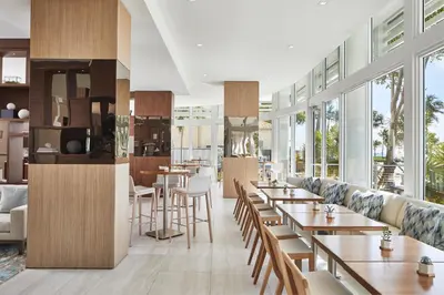 a restaurant with tables and chairs and windows at AC Hotel by Marriott Fort Lauderdale Beach in Fort Lauderdale