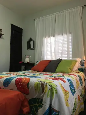 a bed with a colorful comforter and a window at The Jewel of Little Havana in Miami