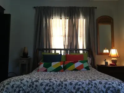 a bed with colorful pillows in front of a window at Private room in the Heart of Little Havana in Miami