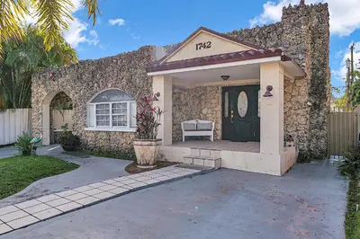 a stone house with a black door and a porch at Boho Studio in Little Havana in Miami