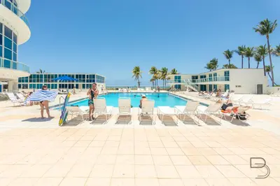 a group of people sitting in chairs by a swimming pool at Girasole Suites in Miami Beach