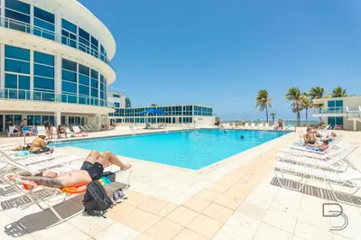 a group of people laying in lawn chairs by a pool at Girasole Suites in Miami Beach