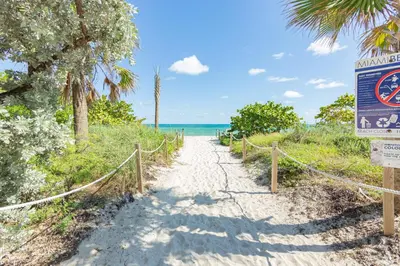a path to the beach with a sign at Girasole Rentals in Miami Beach
