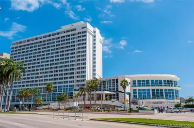 a large white building with palm trees in front of it at Girasole Rentals in Miami Beach