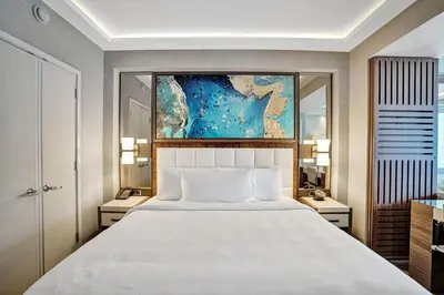 a bedroom with a large bed with a painting above it at Coastal studio w hot tub gym access in Fort Lauderdale