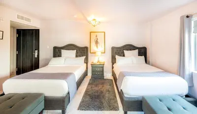 a bedroom with two beds and a bench in it at Secret Garden Miami Beach in Miami Beach