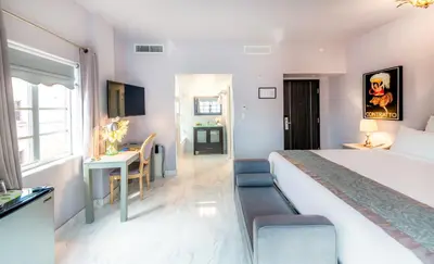 a hotel room with a large bed and a desk at Secret Garden Miami Beach in Miami Beach