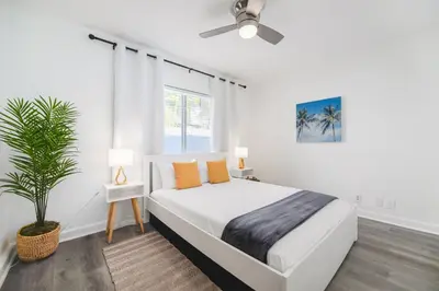 a white bedroom with a bed and a plant at Alani Bay Villas in Fort Lauderdale