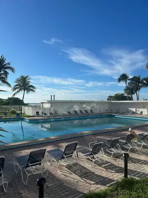 a large swimming pool with chairs and palm trees at Casablanca on the beach in Miami Beach
