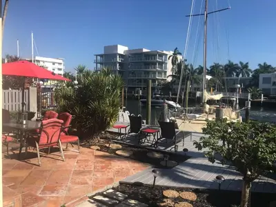 a patio with chairs and a table and a boat at 1BR C direct on the water shared deck Free kayaks in Fort Lauderdale