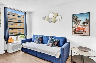 a living room with a blue couch and a window at 1 bedroom in the BEST location in South Beach ! in Miami Beach