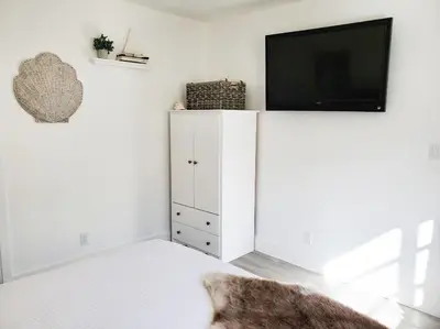 a white cabinet with a flat screen tv on top of it at Stylish & Newly-Renovated Suites near Las Olas in Fort Lauderdale