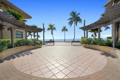 a walkway leading to a resort with palm trees at Little “house” right on the beach in Hollywood