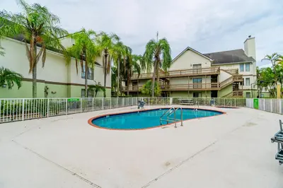 a swimming pool in front of a building with palm trees at Doral Inn & Suites Miami Airport West in Miami