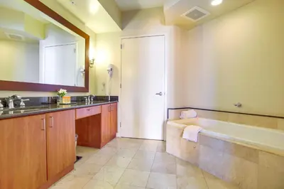 a bathroom with a tub and a sink and a mirror at Pool and Tennis Beachfront Florida Condo! in Miami Beach