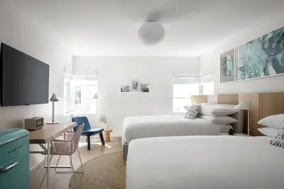 a hotel room with two beds and a desk and a desk at The Kimpton Shorebreak Fort Lauderdale Beach Resort in Fort Lauderdale
