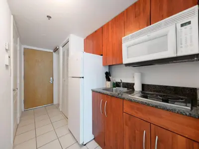 a kitchen with wooden cabinets and a white refrigerator at Cozy and Bohemian Studio in Brickell in Miami