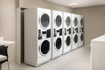 a row of white washing machines in a laundry room at Residence Inn Doral Mall Area in Doral