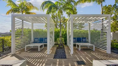 two white benches on a deck with palm trees at Sentral Wynwood in Miami