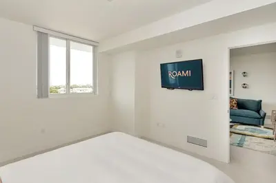 a white room with a bed and a tv on the wall at Roami at Grove 27 in Miami