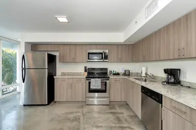 a kitchen with stainless steel appliances and wooden cabinets at Roami at Grove 27 in Miami