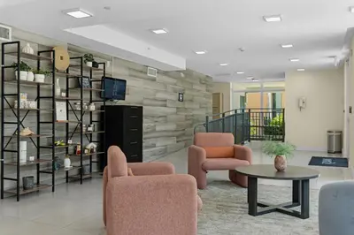 a lobby with two chairs and a table and a tv at Roami at Grove 27 in Miami