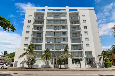 a white building with palm trees in front of it at Roami at Grove 27 in Miami