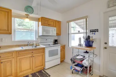 a kitchen with wooden cabinets and a white stove top oven at 2 Mi to Boardwalk Home with Grill in Dania Beach! in Dania Beach