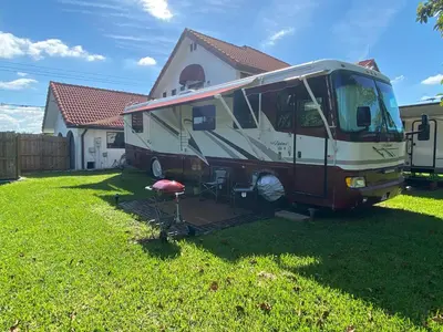 a rv parked in a yard next to a house at Remodeled and Comfortable RV - FREE PARKING in Miami