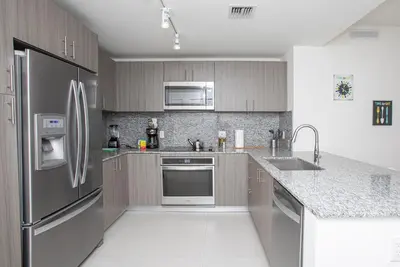 a kitchen with stainless steel appliances and gray cabinets at Luxury 2BD Apartment in Downtown Doral in Miami