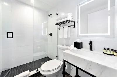 a white bathroom with a toilet and a sink at Upsun Hotel in Miami Beach