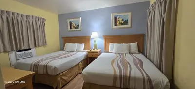 a hotel room with two beds and a table with a lamp at Crown Inn in Fort Lauderdale
