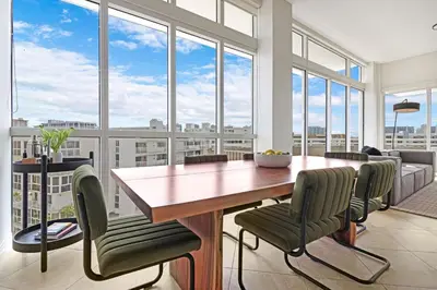 a dining room with a table and chairs and windows at Roami at Sunny Isles in Miami Beach